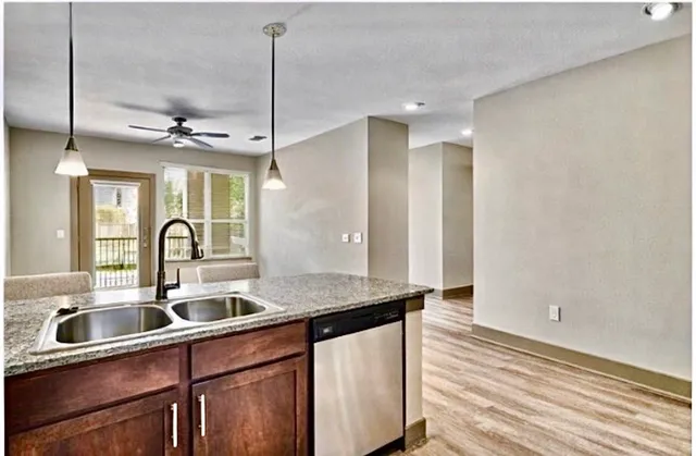 a kitchen with stainless steel appliances granite countertop a sink a counter space and a window