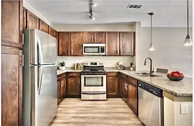 a kitchen with stainless steel appliances granite countertop a refrigerator a stove a sink and a microwave