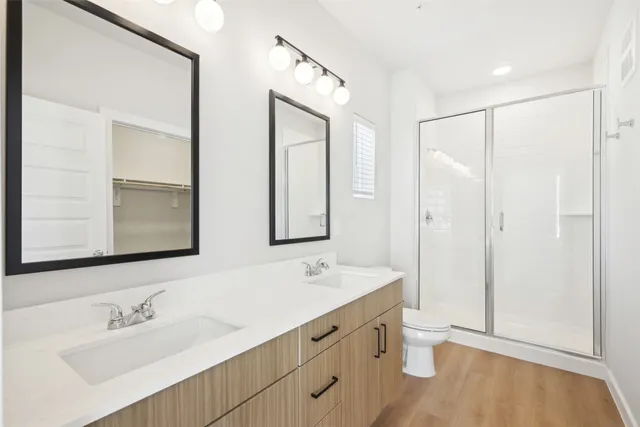 a bathroom with double vanity sink a mirror and a shower