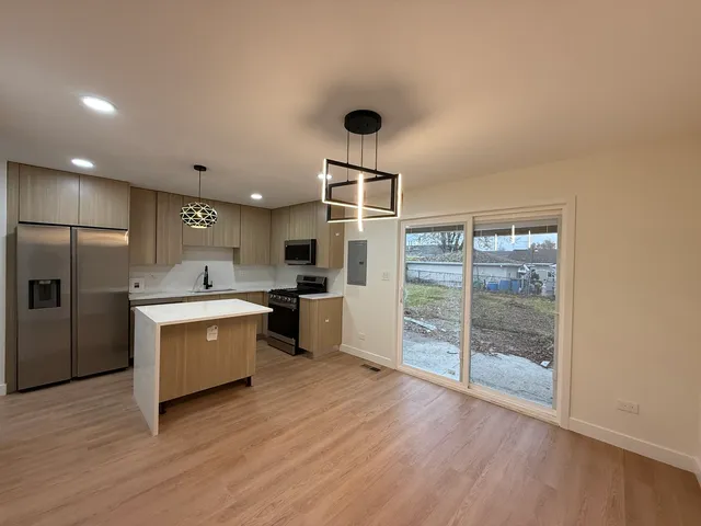 a kitchen with stainless steel appliances a stove top oven a refrigerator a sink and a large window