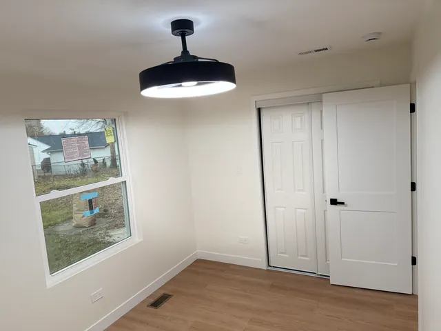 a view of an empty room with a window and wooden floor