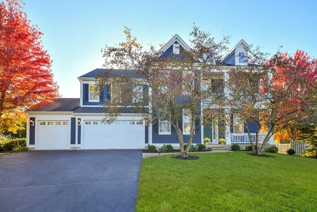 a front view of a house with a garden and tree
