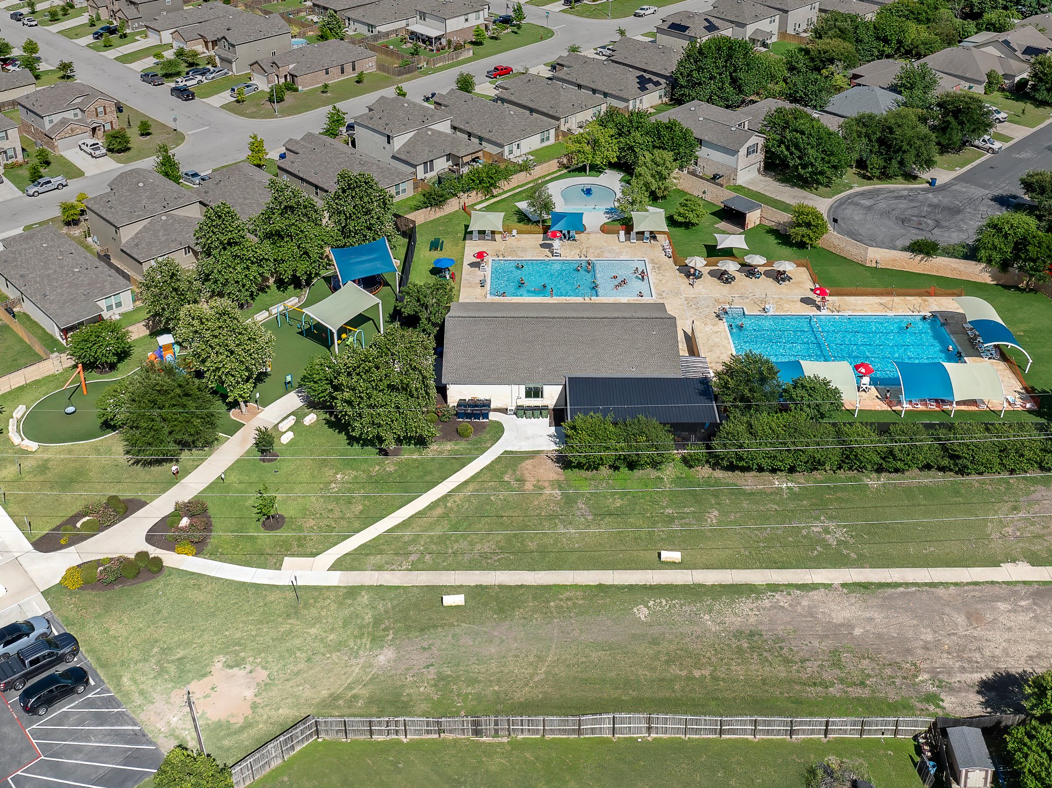 576 Greatest Gift Way Jarrell, TX 76537 - Photo 34 of 37 An aerial view captures the vibrant community amenities, featuring two sparkling pools and a playful park area.