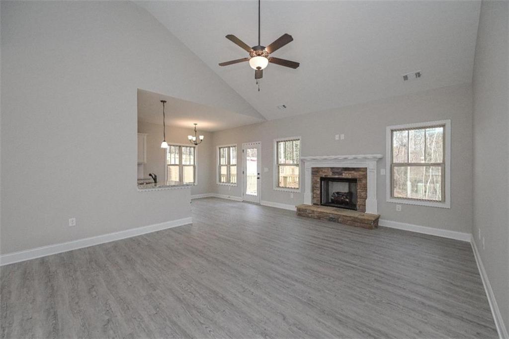 an empty room with wooden floor a fireplace a ceiling fan and windows