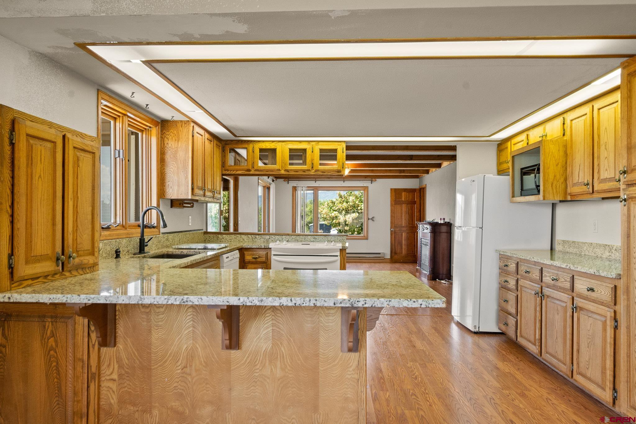 21565 Highway 65 Cedaredge, CO 81413 - Photo 10 of 42 a view of a kitchen with kitchen island a large window a sink and a refrigerator