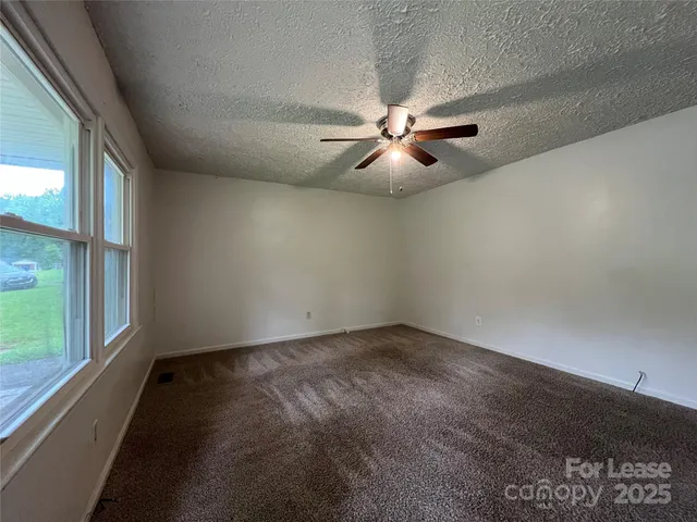 an empty room with a ceiling fan and window