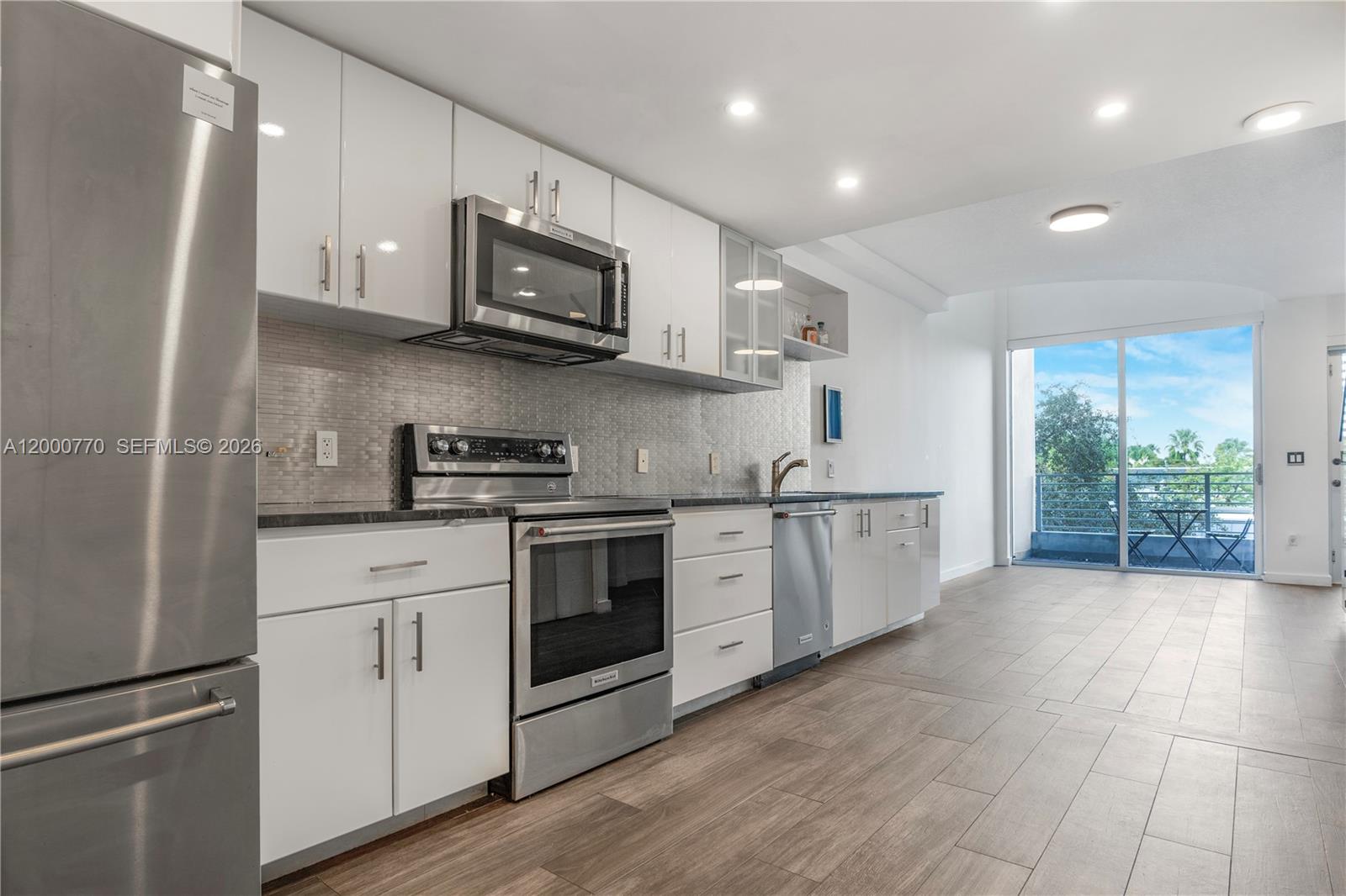 3339 Virginia Street, Unit 339 Miami, FL 33133 - Photo 3 of 24 a kitchen with stainless steel appliances granite countertop a stove a sink and a microwave