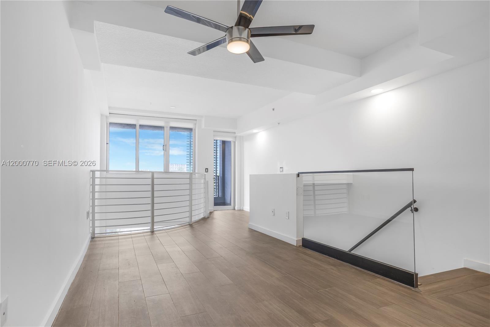 3339 Virginia Street, Unit 339 Miami, FL 33133 - Photo 6 of 24 an empty room with wooden floor chandelier fan and windows