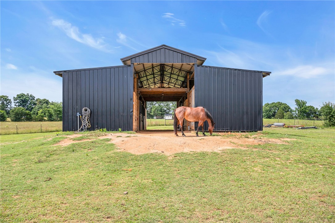 615 Wilson Road Central, SC 29630 - Photo 32 of 50 A spacious, modern metal barn stands on an open grassy pasture under clear blue skies.