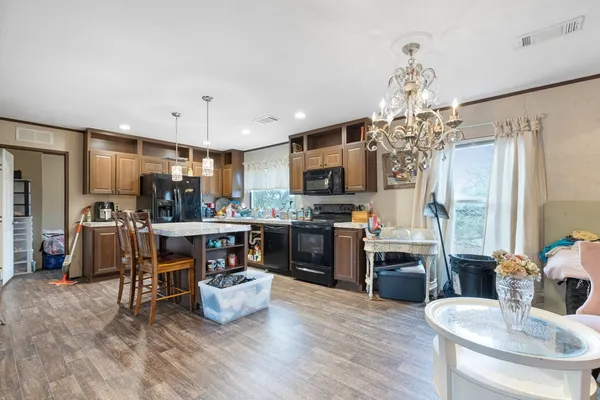 a kitchen with stainless steel appliances kitchen island granite countertop a refrigerator a stove top oven a sink dishwasher and white cabinets with wooden floor