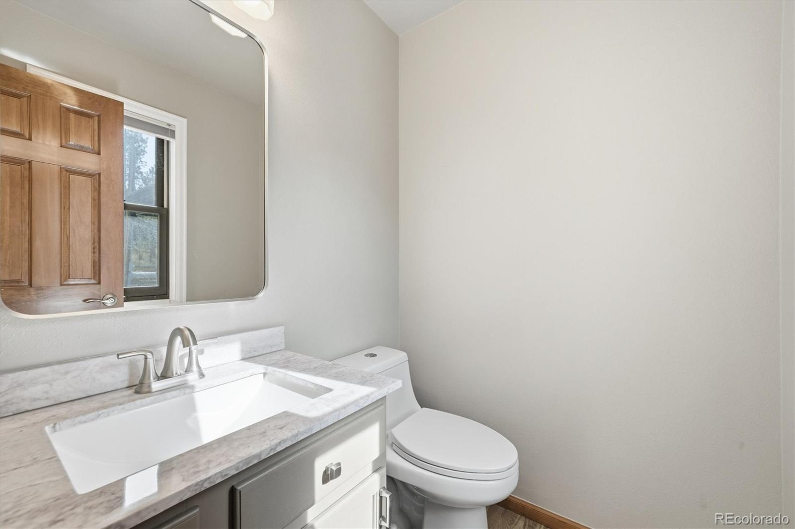 2565 Nova Road Pine, CO 80470 - Photo 14 of 50 a bathroom with a granite countertop sink a toilet and a mirror
