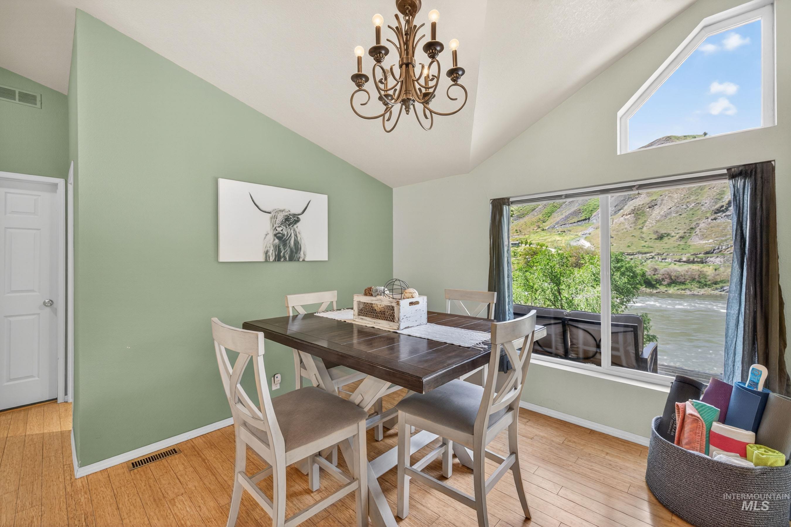 151 Cow Creek Road Lucile, ID 83542 - Photo 14 of 50 Dining area featuring vaulted ceilings, wood-finish flooring, and a large picture window