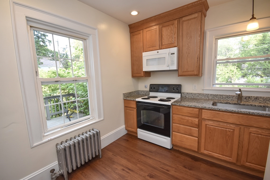 487 Main Street Amherst, MA 01002 - Photo 11 of 39 a kitchen with granite countertop a stove a sink and a window