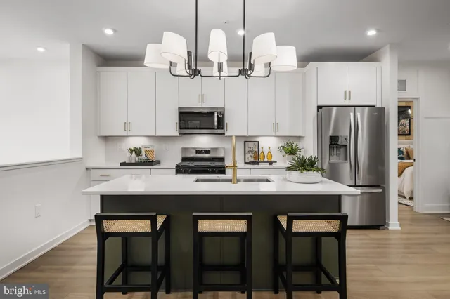 a kitchen with stainless steel appliances granite countertop a sink a stove a refrigerator and island with wooden floor