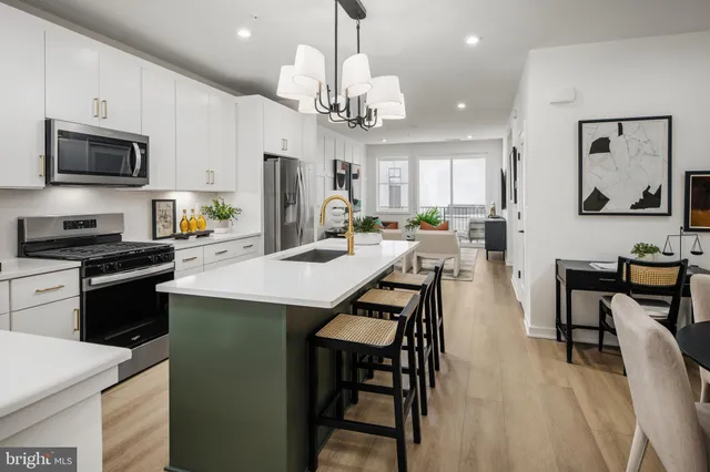 a kitchen with stainless steel appliances kitchen island granite countertop a stove a sink dishwasher a dining table and chairs with wooden floor