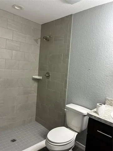 a bathroom with a granite countertop toilet sink and mirror