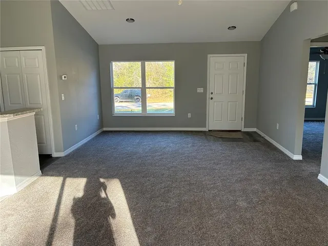 an empty room with windows and ceiling fan
