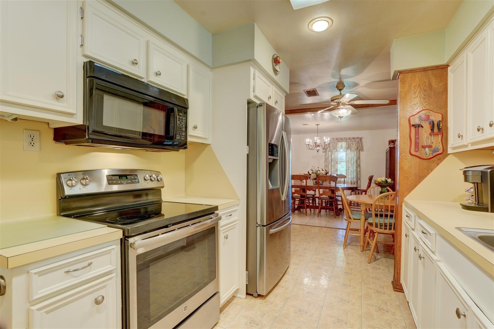 15771 1st Street Splendora, TX 77372 - Photo 11 of 47 a kitchen with stainless steel appliances kitchen island granite countertop a stove top oven a sink a dining table and chairs with wooden floor