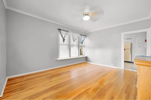 a view of empty room with wooden floor and fan