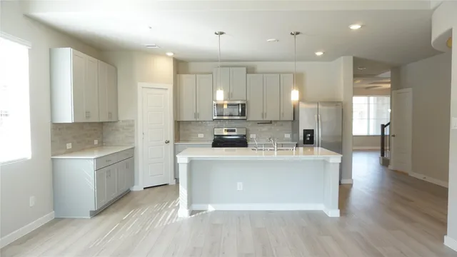 a large kitchen with kitchen island a sink a stove a refrigerator and white cabinets