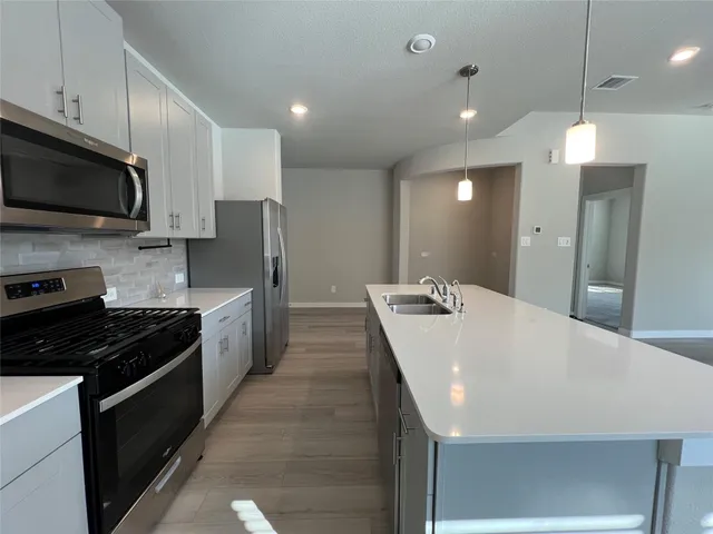 a large kitchen with kitchen island a sink dishwasher stove top oven a refrigerator with cabinets and wooden floor