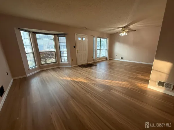 an empty room with wooden floor and windows
