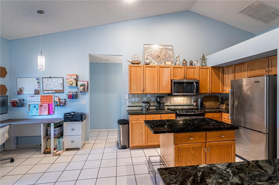 1315 Sabal Lakes Road Delray Beach, FL 33445 - Photo 2 of 38 a kitchen with stainless steel appliances kitchen island granite countertop a refrigerator and a stove top oven