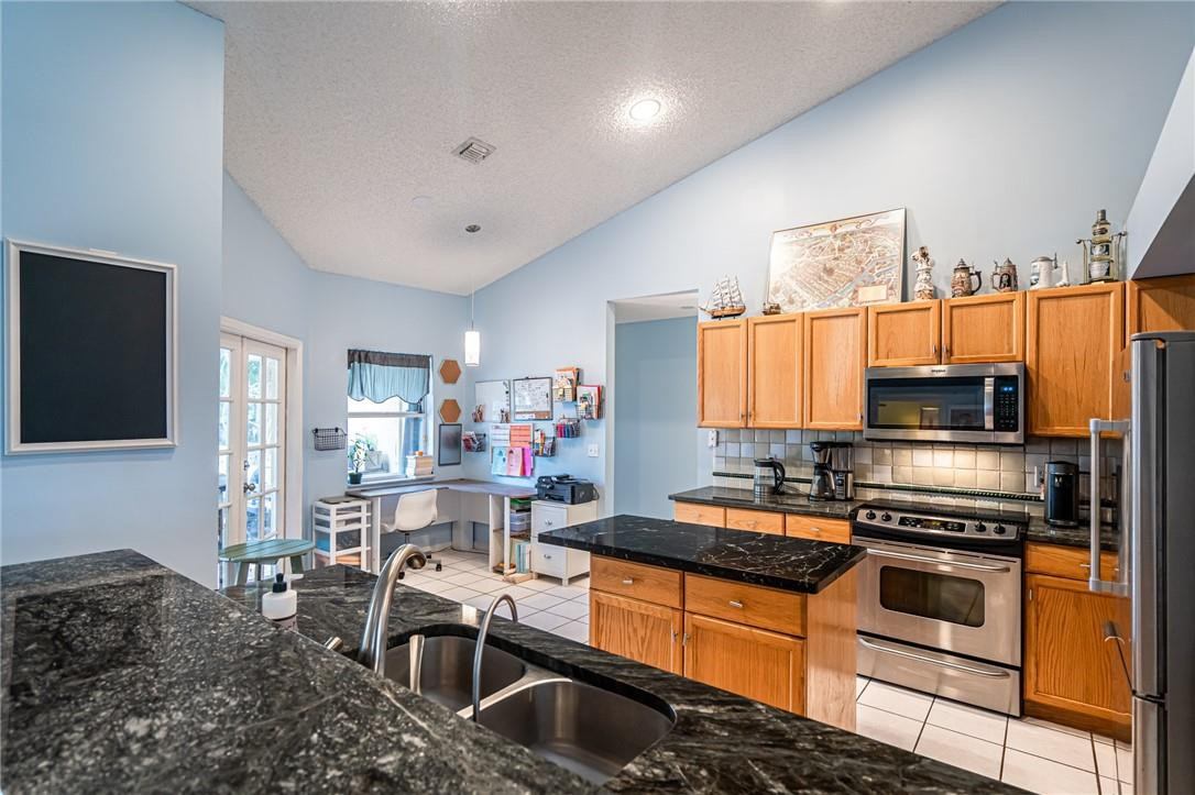 1315 Sabal Lakes Road Delray Beach, FL 33445 - Photo 3 of 38 a kitchen with stainless steel appliances granite countertop a sink stove and refrigerator