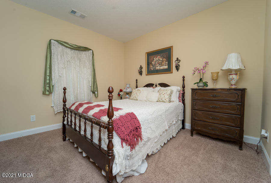 126 Timber Ridge Boulevard Byron, GA 31008 - Photo 17 of 26 a bedroom with a bed and a chandelier
