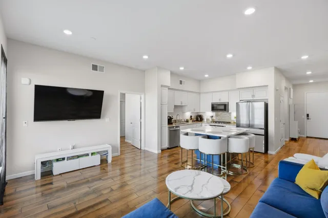 a living room with stainless steel appliances furniture and a kitchen view