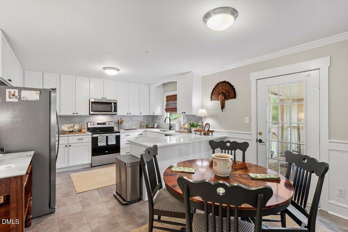 8604 Lobelia Street Raleigh, NC 27603 - Photo 12 of 27 a kitchen with refrigerator cabinets dining table and chairs