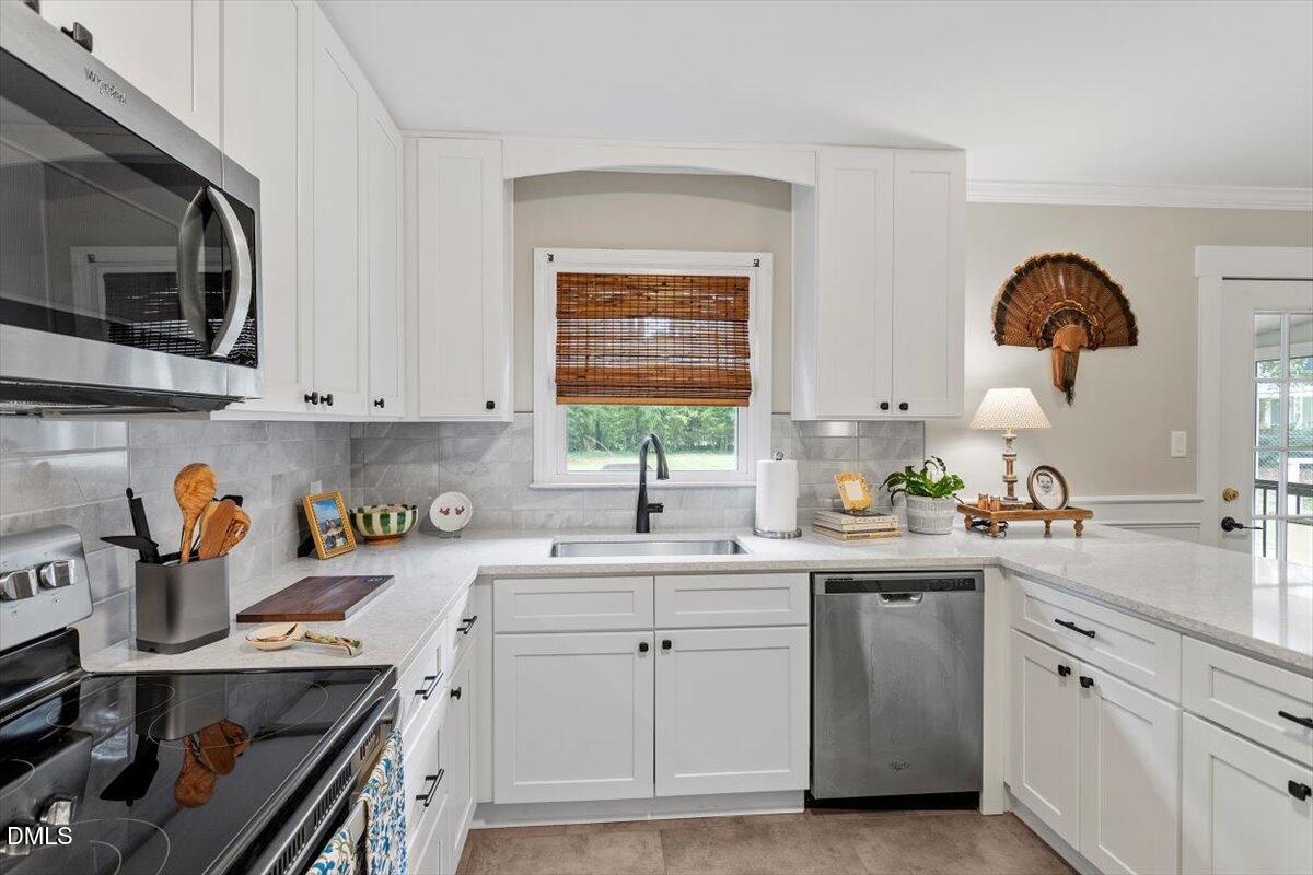 8604 Lobelia Street Raleigh, NC 27603 - Photo 15 of 27 a kitchen with a sink dishwasher and white cabinets with wooden floor