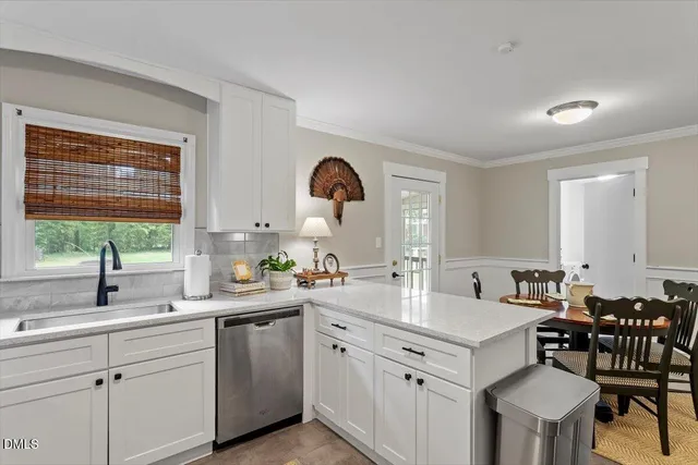 a kitchen with a sink white cabinets and dining table chair