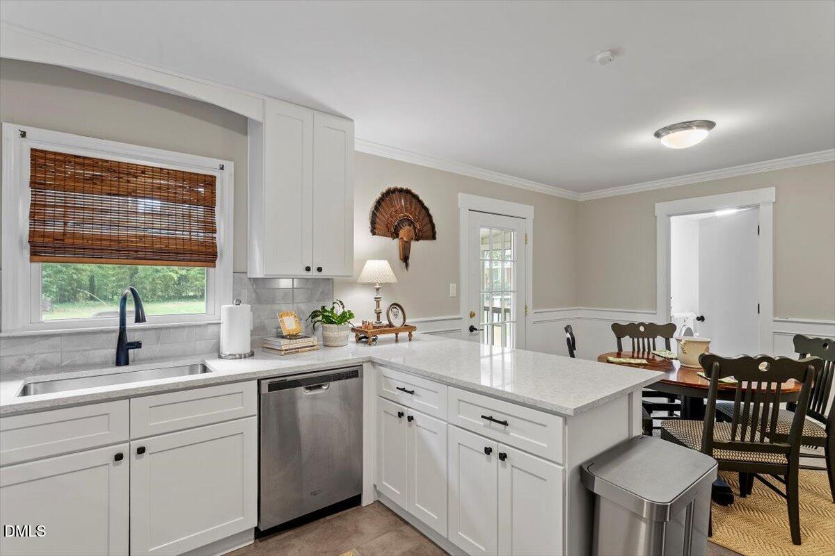 8604 Lobelia Street Raleigh, NC 27603 - Photo 16 of 27 a kitchen with a sink white cabinets and dining table chair