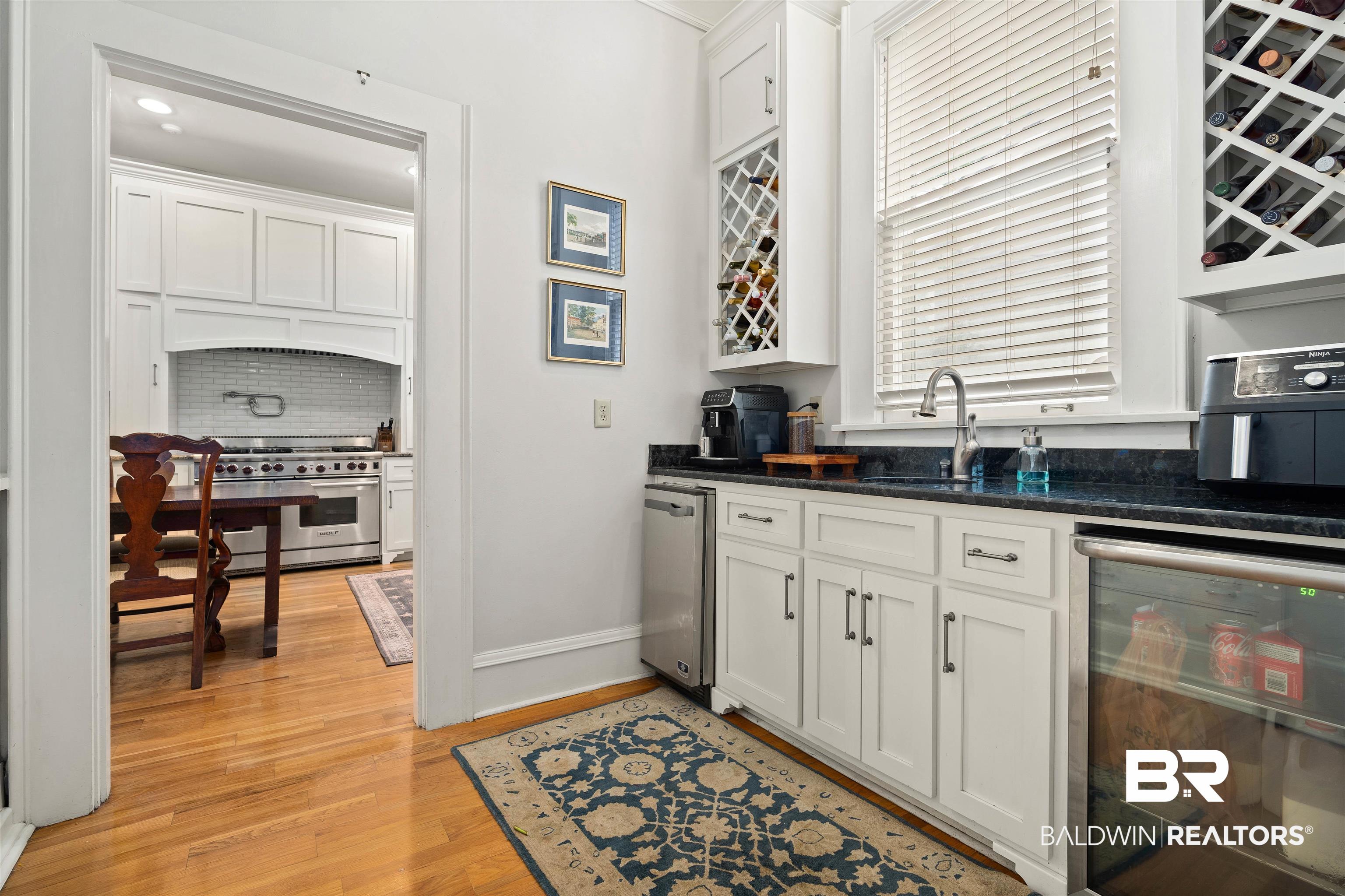 1314 Dauphin Street Mobile, AL 36604 - Photo 21 of 61 Butler's pantry featuring beverage cooler, white cabinets, icemaker, and hardwood