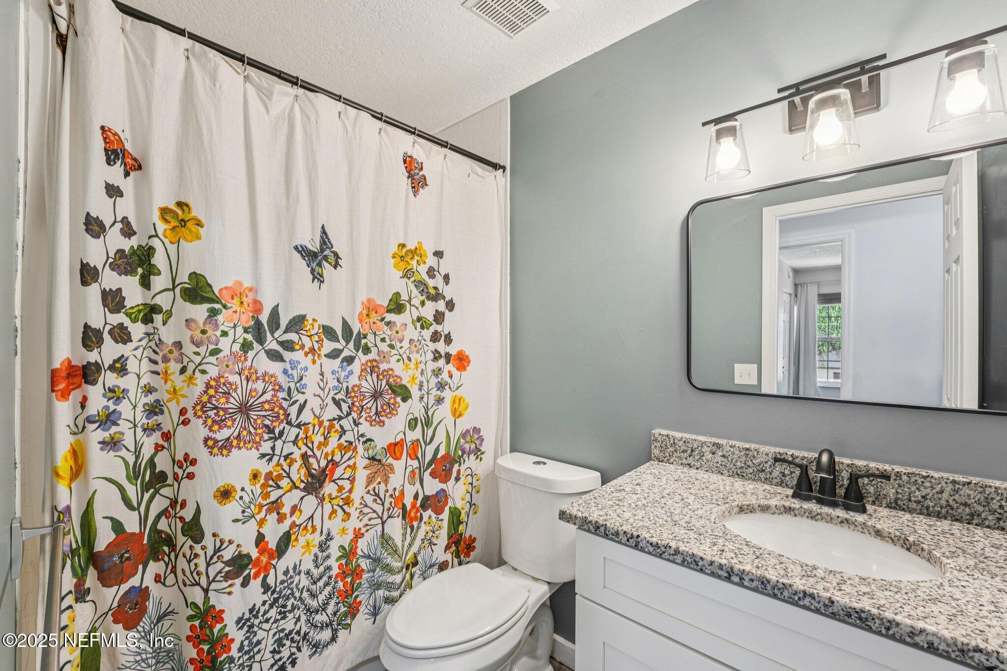 502 Royal Road St. Augustine, FL 32086 - Photo 23 of 34 a bathroom with a granite countertop sink a toilet and a mirror
