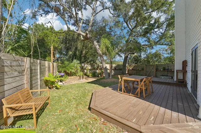 a view of a patio with table and chairs and potted plants with wooden floor and fence