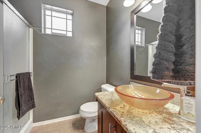 a bathroom with a granite countertop toilet and a sink