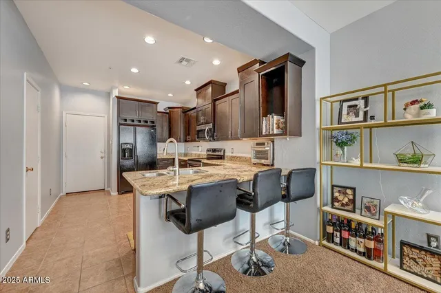 a kitchen with stainless steel appliances kitchen island granite countertop a table chairs and a refrigerator