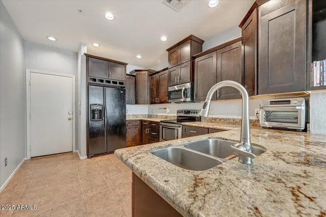a kitchen with stainless steel appliances granite countertop a sink refrigerator and stove