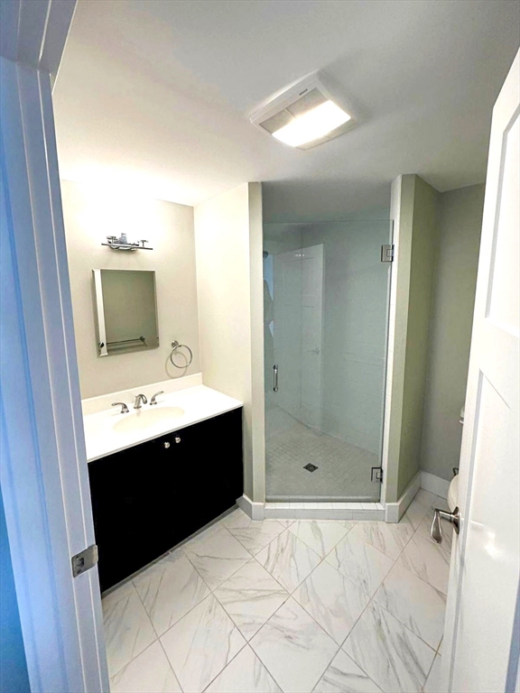 978 Worcester Street, Unit 310 Wellesley, MA 02482 - Photo 6 of 8 a bathroom with a sink mirror and shower