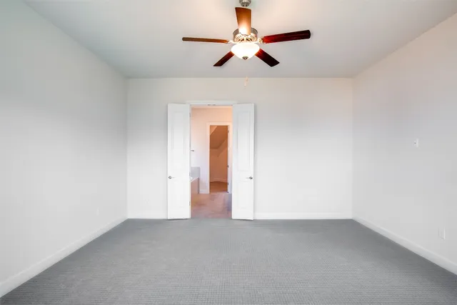 an empty room with a ceiling fan and a window