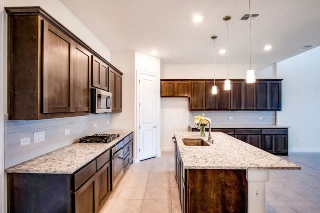 a kitchen with stainless steel appliances granite countertop a kitchen island a stove and a sink