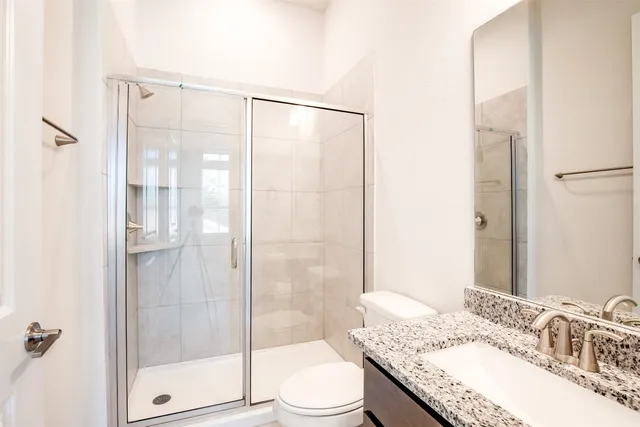 a bathroom with a granite countertop sink toilet and shower