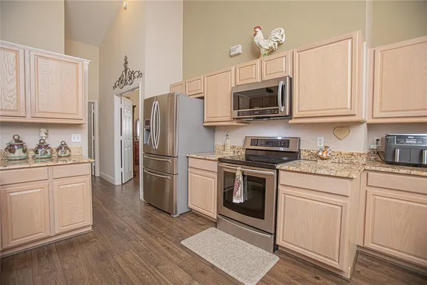 a kitchen with granite countertop a refrigerator stove and white cabinets