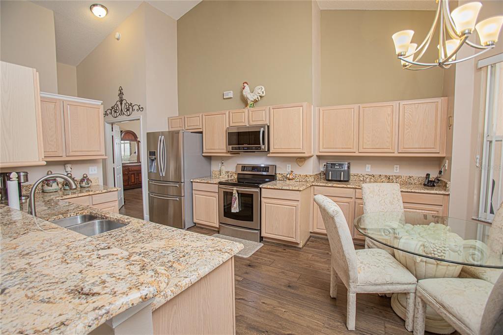3321 Furlong Way Gotha, FL 34734 - Photo 12 of 26 a kitchen with granite countertop a stove top oven a sink dishwasher a dining table and chairs with wooden floor