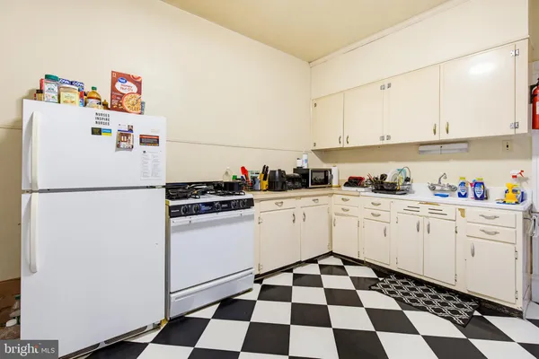a kitchen with a checkered floor and white cabinets