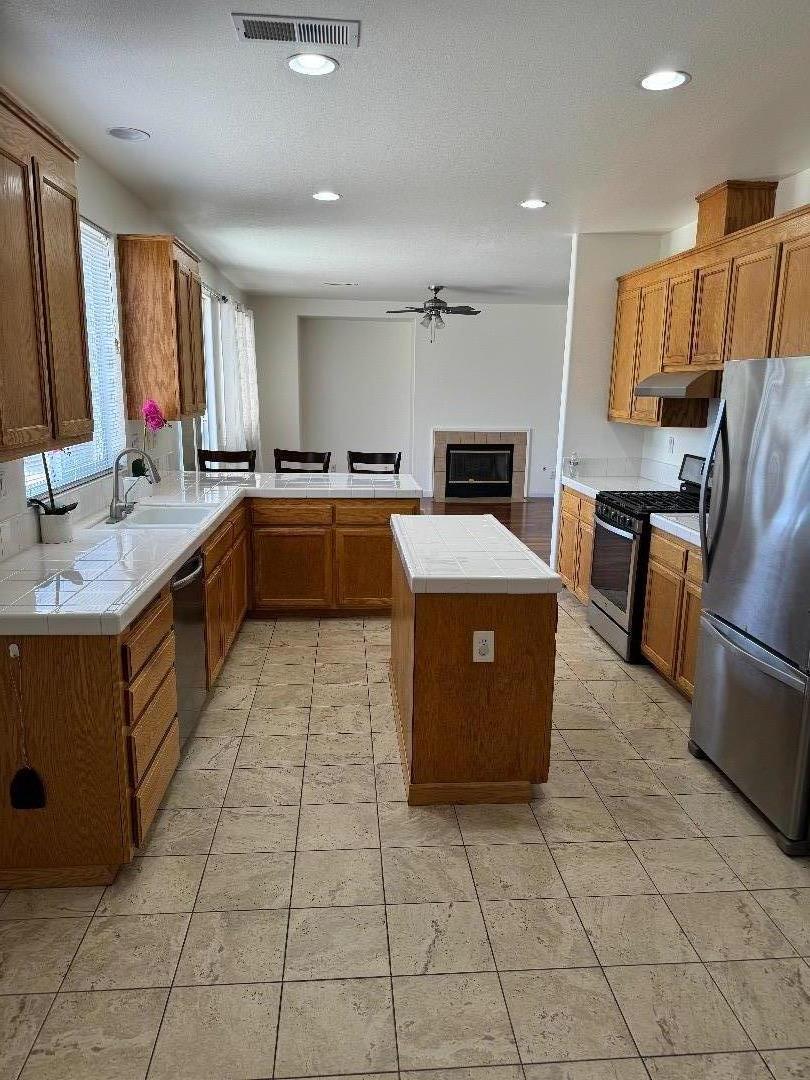 949 Terraza Street Soledad, CA 93960 - Photo 8 of 38 a large kitchen with kitchen island a stove a sink dishwasher and white cabinets
