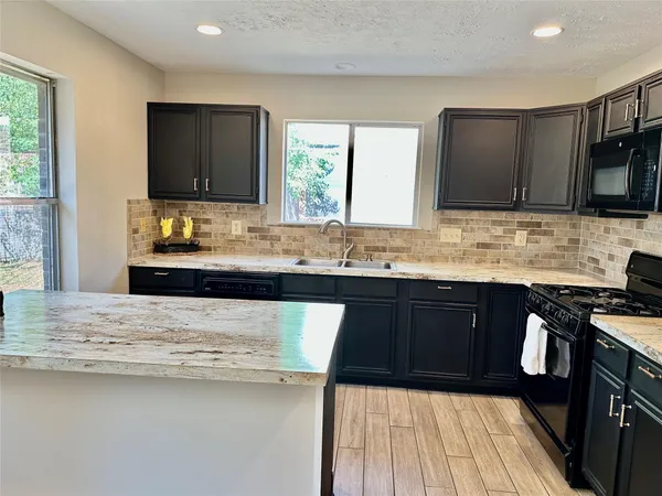 a kitchen with granite countertop a sink and wooden cabinets