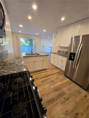 a large kitchen with stainless steel appliances granite countertop a stove a sink and a refrigerator